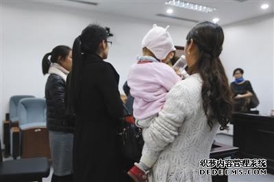 昨日,一名当事女员工抱着孩子在法庭上接受记者采访。新京报记者 王贵彬 摄